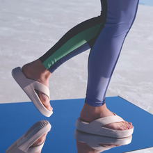 Load image into Gallery viewer, Person wearing white sandals and colorful leggings on a blue surface with a light gray background